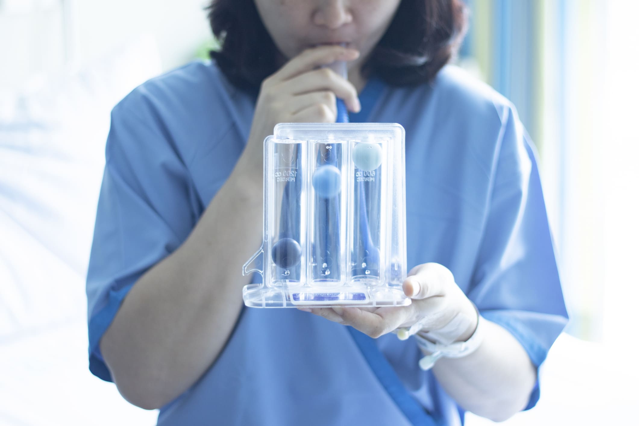 Persona usando un espirómetro incentivador para ejercicios de prehabilitación respiratoria en preparación para tratamiento oncológico.
