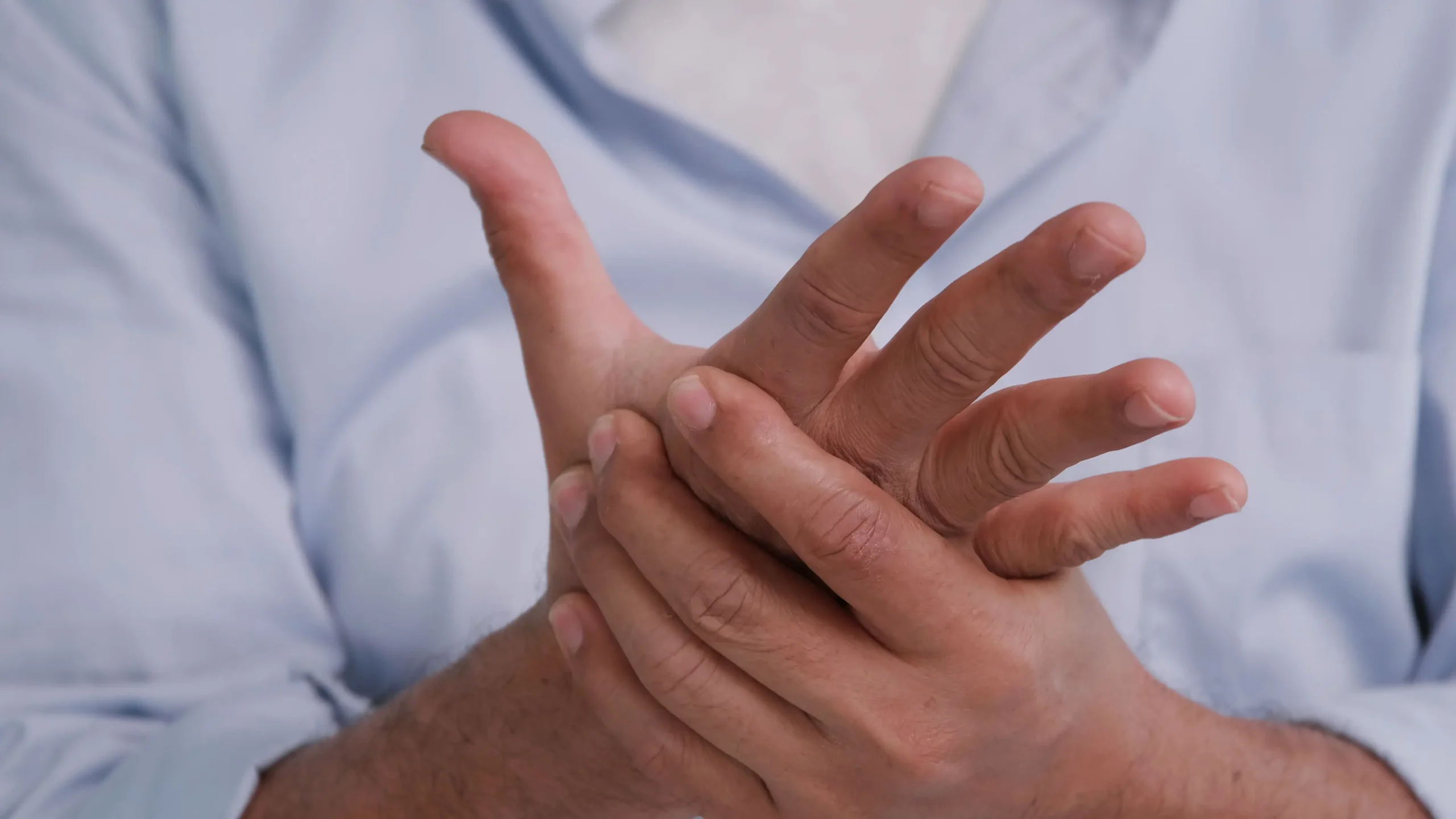Primer plano de una persona masajeando su mano para aliviar el hormigueo y la entumecimiento, síntomas comunes de la neuropatía por quimioterapia.