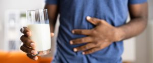 Hombre con dolor despues de tomar un vaso de leche debido a una intolerancia alimentiaria