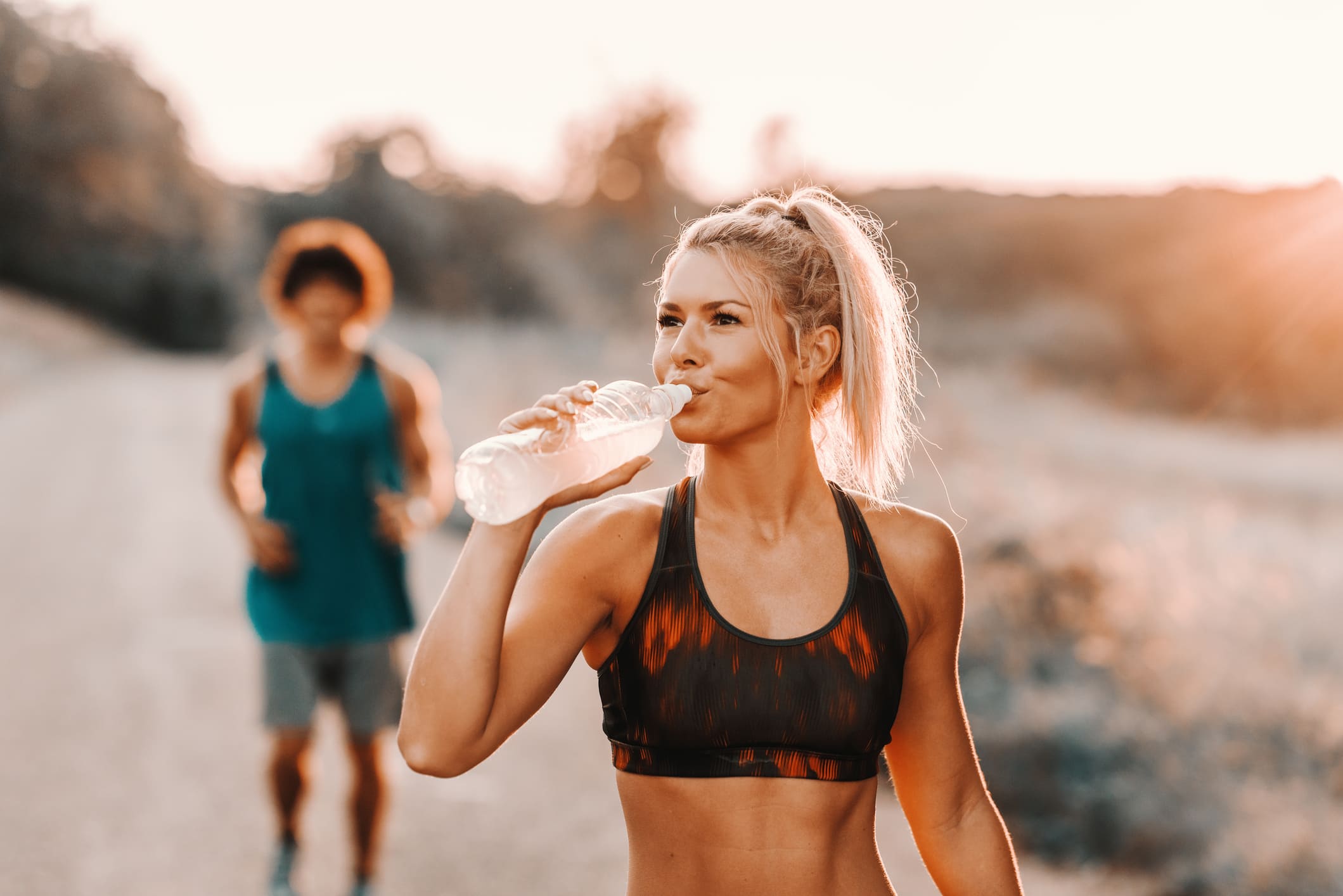 Mujer hidratándose durante una sesión de running al aire libre, ideal para entrenamientos de maratón.